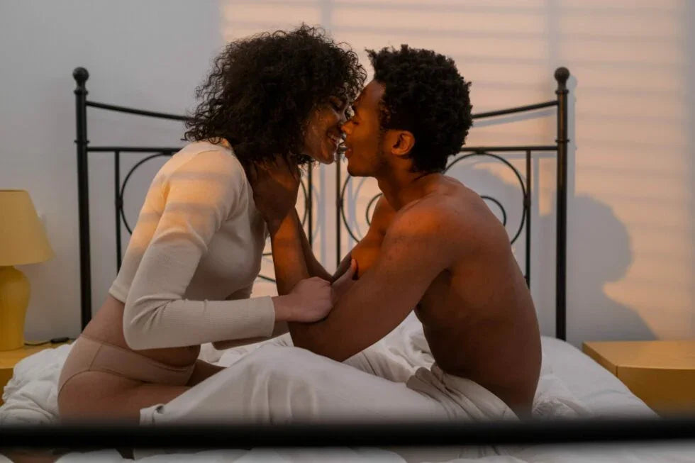 Couple sitting on bed intimately facing each other with soft lighting and cozy bedroom setting
